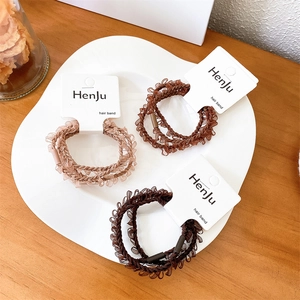 Three-piece hair tie set in brown shades with lace trim on a ceramic tray