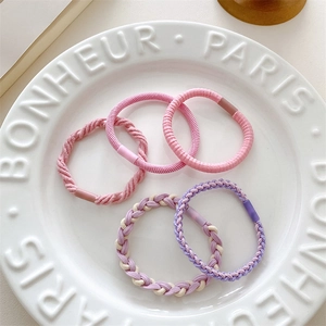 Close-up of five macaron-colored elastic hair ties on a decorative white porcelain plate