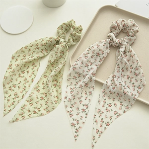 Close-up of floral chiffon scrunchies with long ribbons in light green and cream white colors