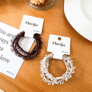 Close-up of lace hair ties in brown and cream colors with branded display card packaging