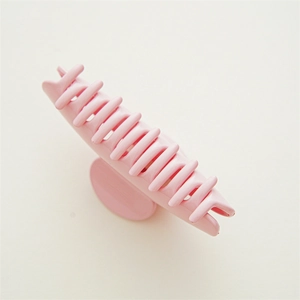 Detailed top view of a large pink shark clip with a glossy finish for thick hair styling