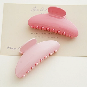 Detailed view of high-gloss pink hair claw clips on artistic beige card stationery