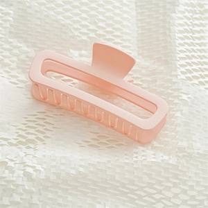 Detail view of pink matte hair claw clip for thick hair on white textured background