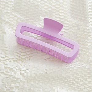 Detail of a matte lavender purple rectangular claw clip on a textured white background