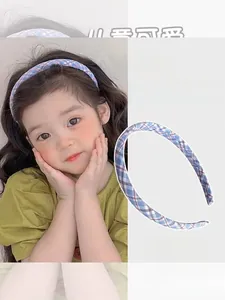 Detail of blue and red plaid fabric headband showing high elasticity on a child model
