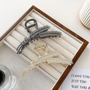 Elegant wheat ear hair claws in gold and gunmetal with crystals on wooden display