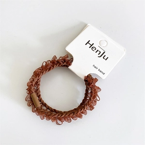 Close-up of brown pleated hair band with glossy texture on white display card