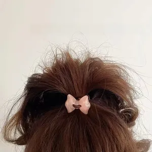 Pink resin bow hair tie shown on long hair with a jelly-like translucent texture
