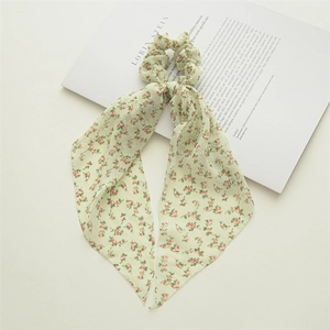 Detail of light green floral chiffon hair scrunchie with long ribbons on a magazine