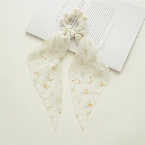 Detailed view of floral chiffon scrunchie with streamers on an aesthetic background