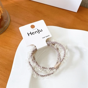 Close-up of elegant mocha brown lace hair ties with elastic cords on a ceramic tray