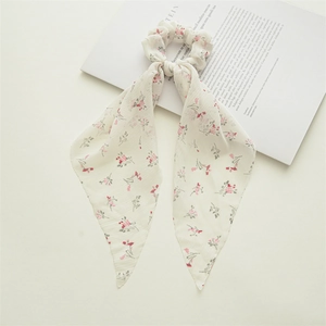 Detail view of cream floral scrunchie with ribbons featuring pink flowers and green leaves