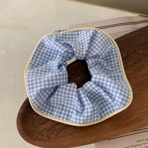 Detalle de coletero a cuadros azules y blancos con borde crema en bandeja de madera