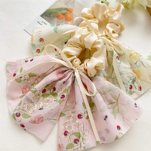 Détail de la broderie florale sur chouchous roses et beige avec longs rubans