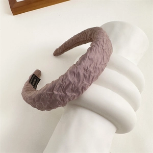 Close-up of pleated sponge headband with handmade label and dried rose fabric texture