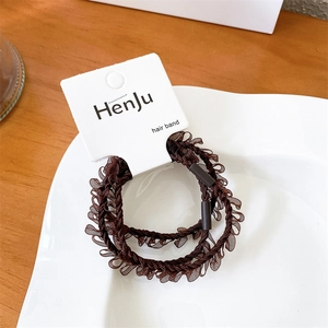 Detail of two dark brown mesh hair bands with ruffle texture on a white ceramic plate