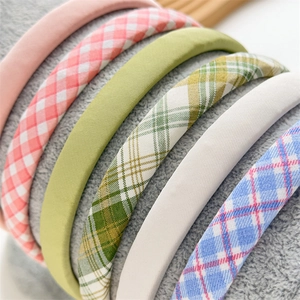 Assorted colorful plaid and solid cotton headbands displayed on soft grey texture