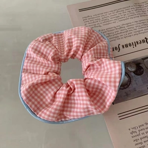 Detalle de coletero de cuadros rosas con borde azul sobre un fondo estético minimalista
