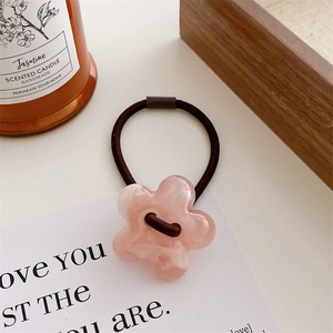 Close-up of pink jelly-colored flower hair tie with marble texture on white card