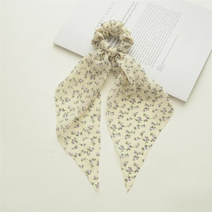 Close-up of cream floral scrunchie with long ribbons on a white magazine background
