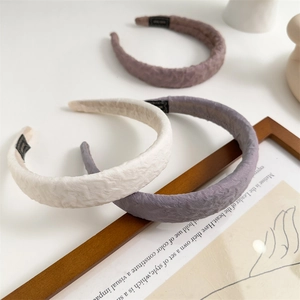 Three padded sponge headbands in cream, mauve, and dusty rose on a wooden frame