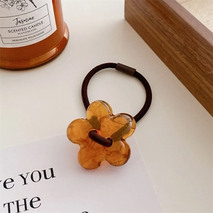 Detail view of amber resin flower hair tie with high elastic band on a warm background