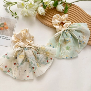 Détail de broderies florales sur chouchous en tulle avec longs rubans et texture satin