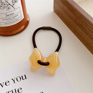 Detail of yellow amber resin bow hair tie with high-elastic dark brown rubber band