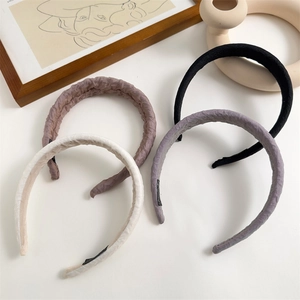 Detail view of four pleated fabric headbands in black, lilac, pink, and cream colors