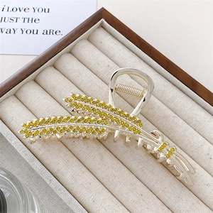 Detail showing wheat ear hair claw clip with golden finish and amber rhinestones in box