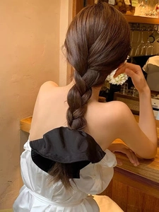 Detailed view of an oversized black satin scrunchie styled on hair in a cozy cafe setting