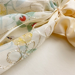 Détail macro du chouchou floral avec broderie fraise et nœud en satin jaune
