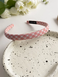 Detail of pink plaid fabric headband on a white decorative plate with handmade label