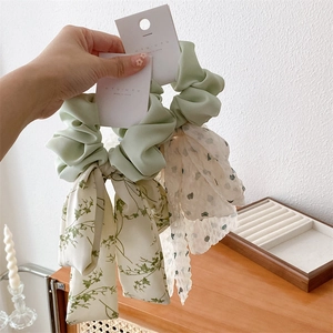 Détail de chouchou en satin vert menthe et ruban en mousseline florale avec nœud élégant