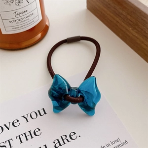 Macro detail of dark blue translucent resin bow hair tie with brown elastic band