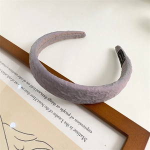 Detail of lavender pleated fabric headband resting on a wooden frame with smooth textures
