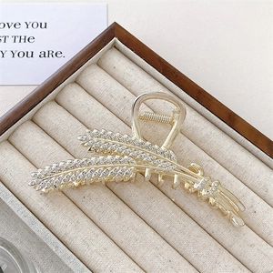 Detailed macro view of wheat-shaped golden hair claw clip with inlaid sparkling rhinestones