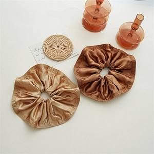 Detailed close-up of champagne and coffee satin scrunchies with smooth silk texture