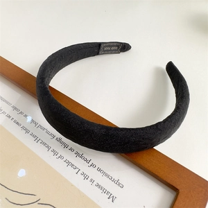 Detail of a black wide fabric headband with sponge padding and a Hand Made label