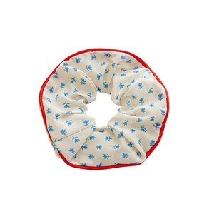 Coletero floral con estampado de flores azules y borde rojo en fondo blanco