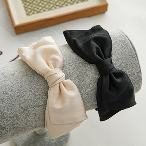 Detailed close-up of large satin bow headbands in black and champagne on a display stand