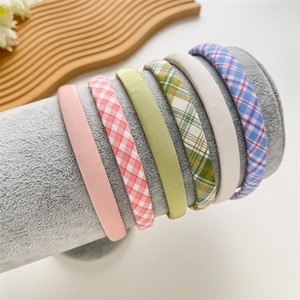 Close-up set of six colorful plaid and solid fabric headbands on a velvet display stand