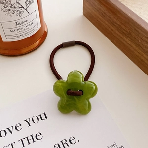 Close-up of green resin flower hair tie with high-elastic rope on white paper
