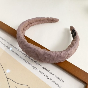 Detail of a pink pleated sponge headband with fabric texture on a wooden frame
