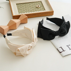 Close-up of beige and black satin knot headbands with oversized bows on a desk