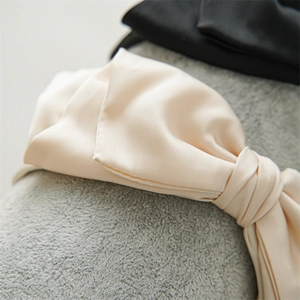 Close-up of elegant champagne satin fabric bow headband with smooth silk texture