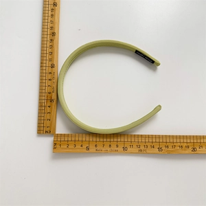 Detail view of a light green plaid headband featuring a hand-made woven fabric label
