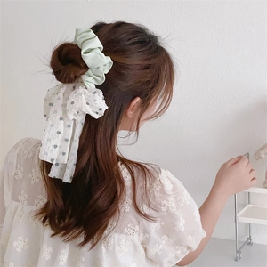 Vue détaillée du chouchou vert menthe avec ruban à cœurs blancs sur les cheveux