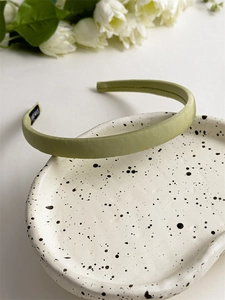 Detailed view of light green plaid headband with handmade label and woven texture