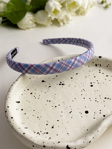 Detail of pink and blue plaid fabric headband with handmade tag on ceramic tray